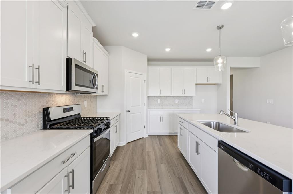 1499 High Fls Lane Grayson, GA 30017 - Photo 13 of 37 a kitchen with stainless steel appliances a sink dishwasher a stove top oven a refrigerator with white cabinets and wooden floor