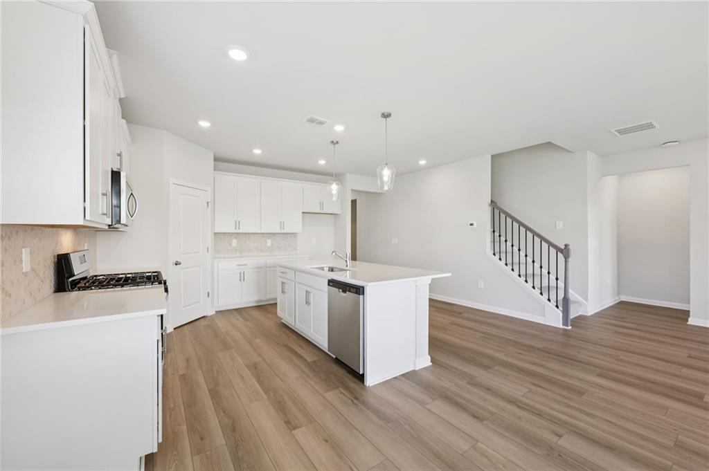 1499 High Fls Lane Grayson, GA 30017 - Photo 14 of 37 a kitchen with wooden floors and white cabinets