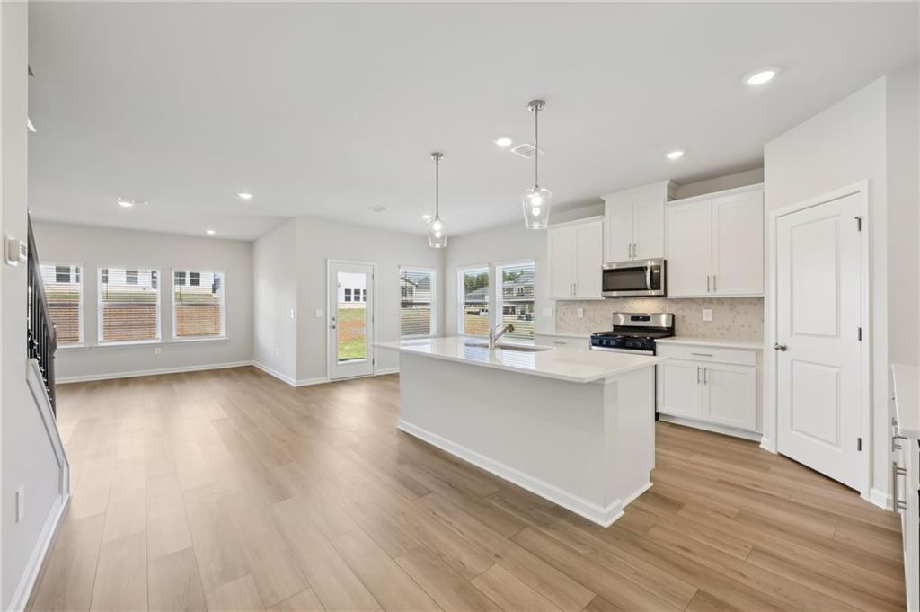 1499 High Fls Lane Grayson, GA 30017 - Photo 9 of 37 a kitchen with stainless steel appliances kitchen island hardwood floor sink and stove