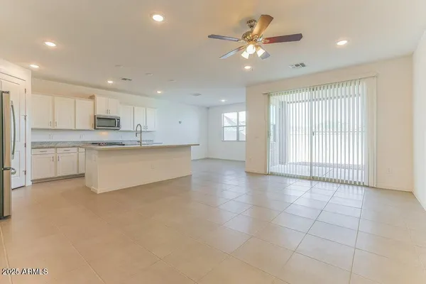 a large kitchen with stainless steel appliances granite countertop a stove a sink a refrigerator and white cabinets with wooden floor