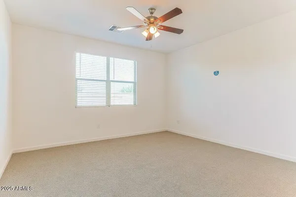 an empty room with a window and a fan