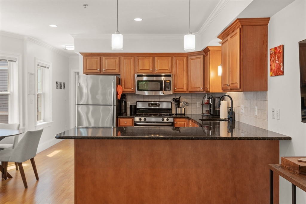 17 Robbins Street, Unit 22 Waltham, MA 02453 - Photo 4 of 27 a kitchen with stainless steel appliances granite countertop a refrigerator a stove and a sink with wooden floor