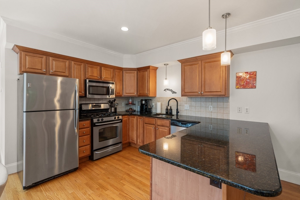 17 Robbins Street, Unit 22 Waltham, MA 02453 - Photo 6 of 27 a kitchen with stainless steel appliances granite countertop a refrigerator sink stove microwave and cabinets