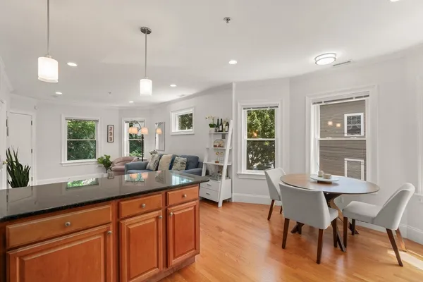 a dining hall with stainless steel appliances granite countertop wooden floor a dining table and chairs