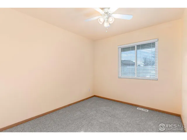 an empty room with a window and a ceiling fan