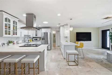 a living room with stainless steel appliances furniture a flat screen tv and kitchen view