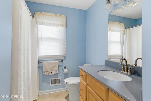 a bathroom with a granite countertop sink toilet and mirror