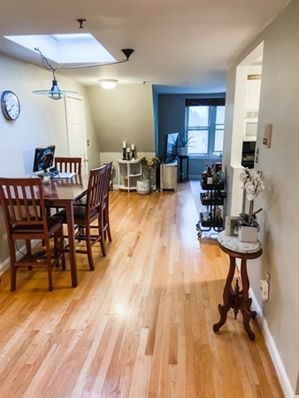 122 Tudor Street, Unit D Boston, MA 02127 - Photo 2 of 8 a dining room with furniture a chandelier and wooden floor