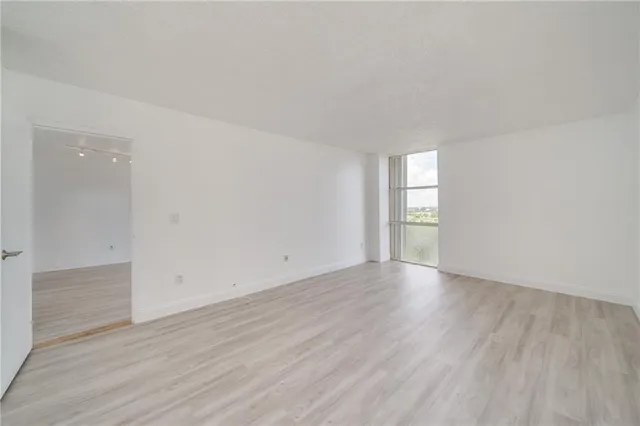 an empty room with wooden floor and window