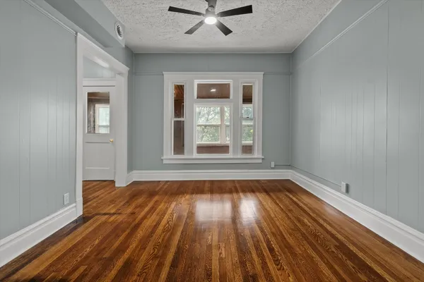 a view of empty room with wooden floor and fan