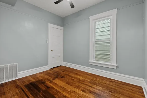 a view of empty room with wooden floor and fan