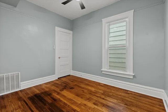 a view of empty room with wooden floor and fan