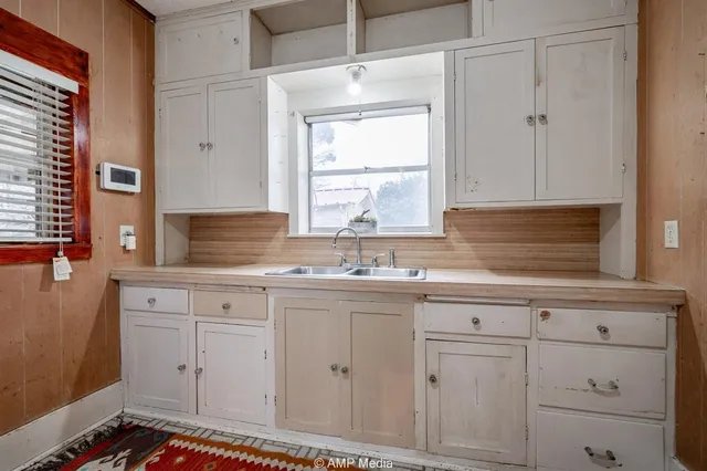 a kitchen with white cabinets and sink