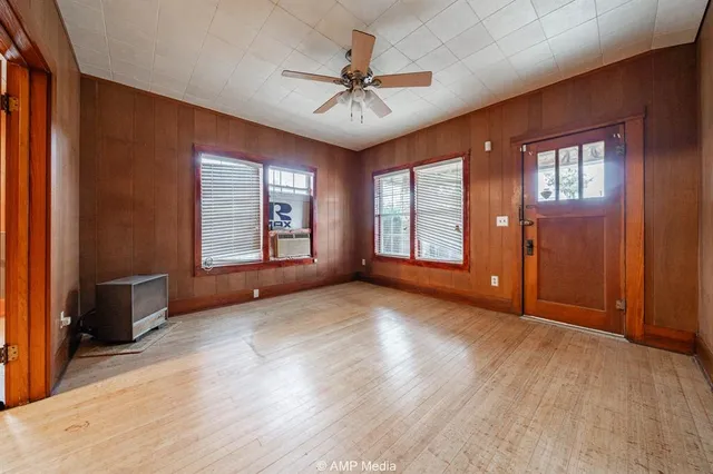 an empty room with windows and ceiling fan