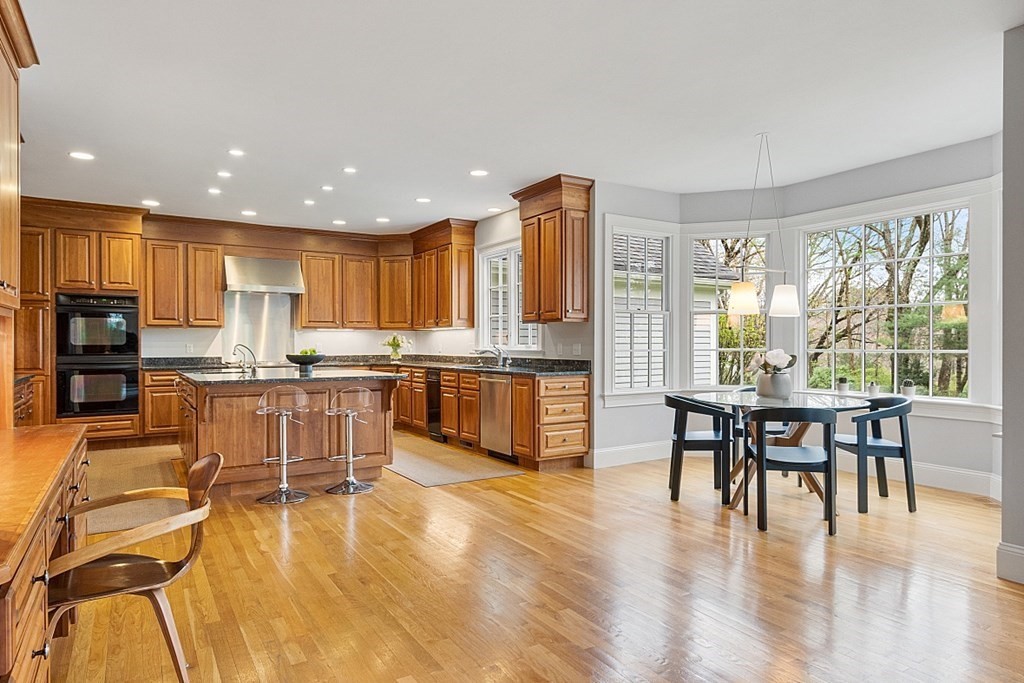 257 Nashoba Road Concord, MA 01742 - Photo 13 of 41 a kitchen with stainless steel appliances granite countertop a stove top oven a sink a dining table and chairs with wooden floor