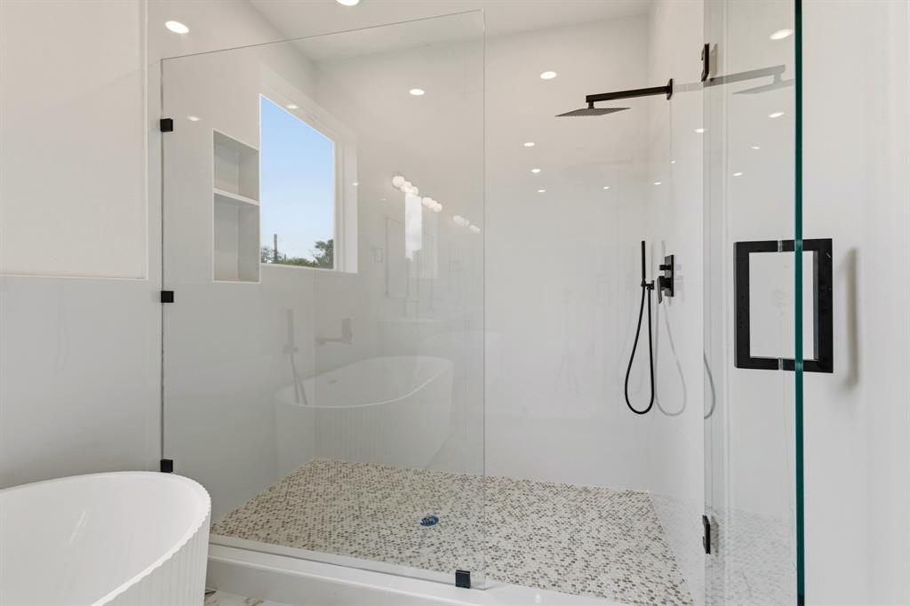 415 North Patton Avenue Dallas, TX 75203 - Photo 11 of 20 Modern bathroom featuring a glass-enclosed shower with a mosaic tile floor, matte black shower fixtures, and a free-standing bathtub