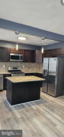 a kitchen with stainless steel appliances kitchen island granite countertop a stove a sink and a microwave