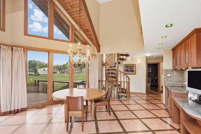 a view of a dining room with furniture a chandelier and kitchen view