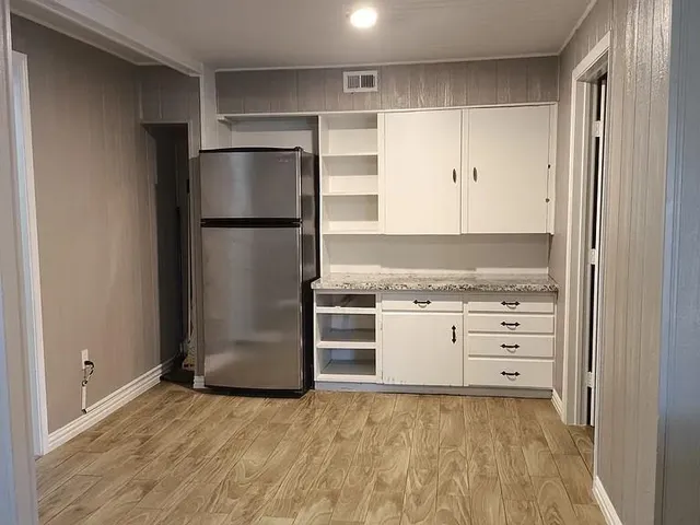 a kitchen with granite countertop a refrigerator and a stove top oven