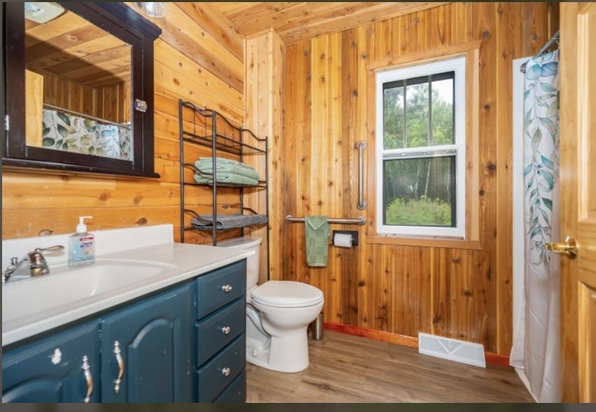 126 Jay Cooke Road Esko, MN 55733 - Photo 14 of 19 Bathroom with wooden walls, wood finished floors, vanity, and curtained shower