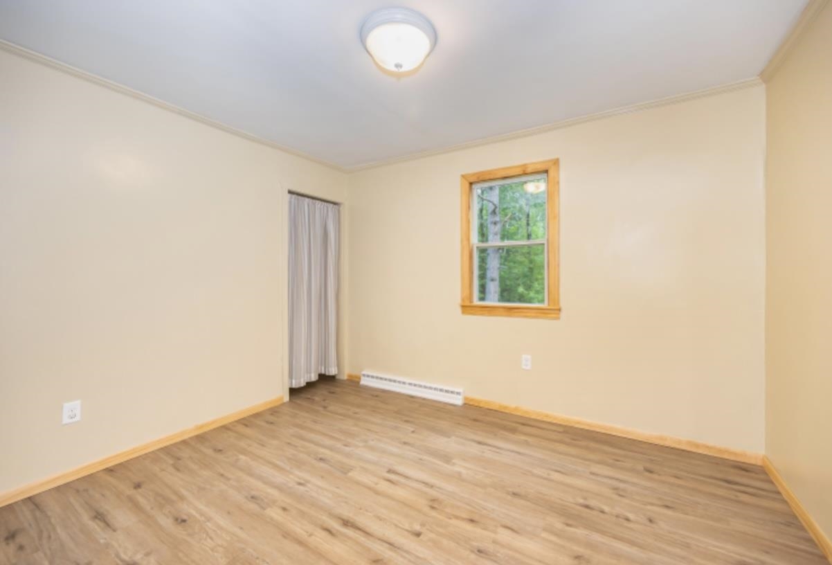 126 Jay Cooke Road Esko, MN 55733 - Photo 9 of 19 Empty room with light wood-style floors and a baseboard radiator