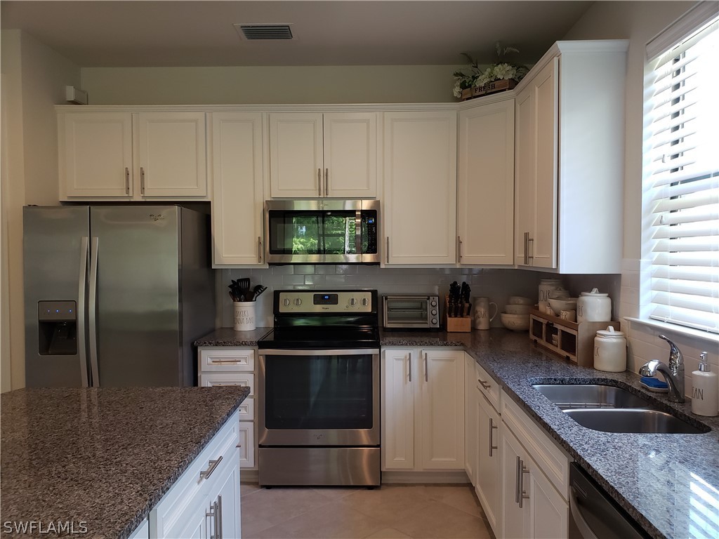 3336 Hampton Boulevard Fort Myers, FL 33905 - Photo 12 of 29 a kitchen with stainless steel appliances granite countertop a sink a stove and a refrigerator