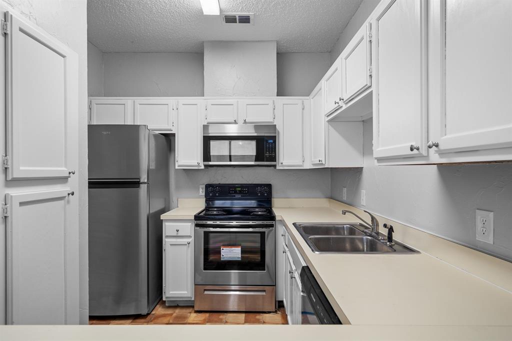 5310 Keller Springs Road, Unit 626 Dallas, TX 75248 - Photo 6 of 13 a kitchen with white cabinets and stainless steel appliances