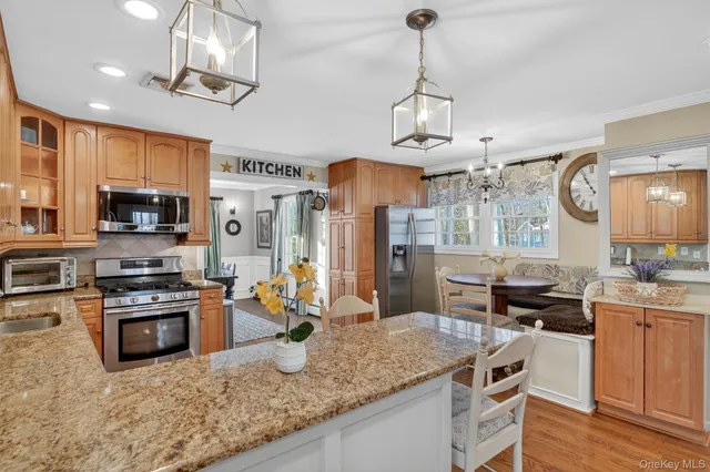 a kitchen with stainless steel appliances granite countertop a stove top oven a sink dishwasher a dining table and chairs with wooden floor