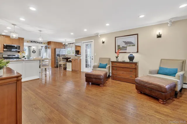 a kitchen with stainless steel appliances kitchen island granite countertop a refrigerator a stove top oven a sink dishwasher and white cabinets with wooden floor