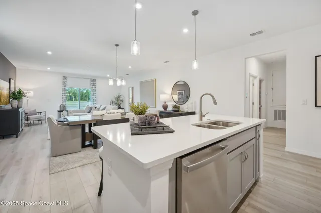 a kitchen with kitchen island a sink a counter space and living room view