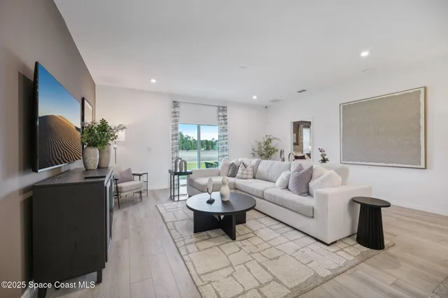 a living room with furniture a flat screen tv and a window