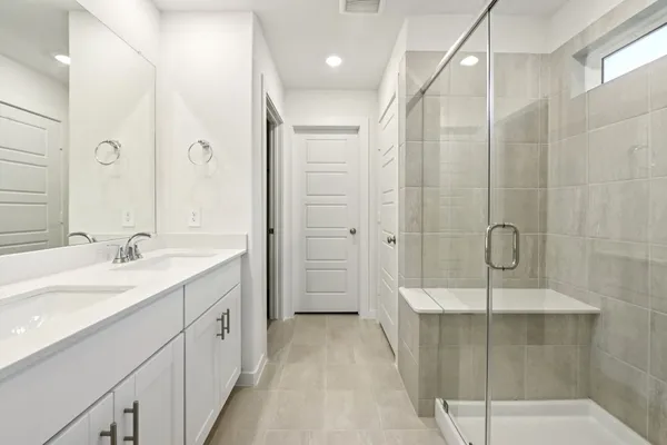 a bathroom with a double vanity sink mirror and shower