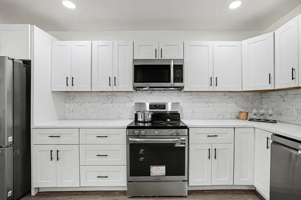 a kitchen with white cabinets and stainless steel appliances