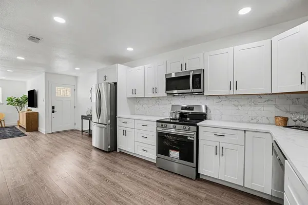 a kitchen with a refrigerator stove and white cabinets