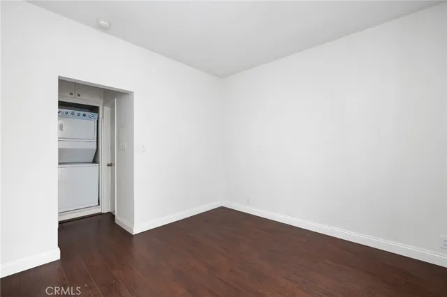 a view of an empty room with wooden floor and closet