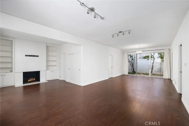 an empty room with wooden floor fireplace and windows