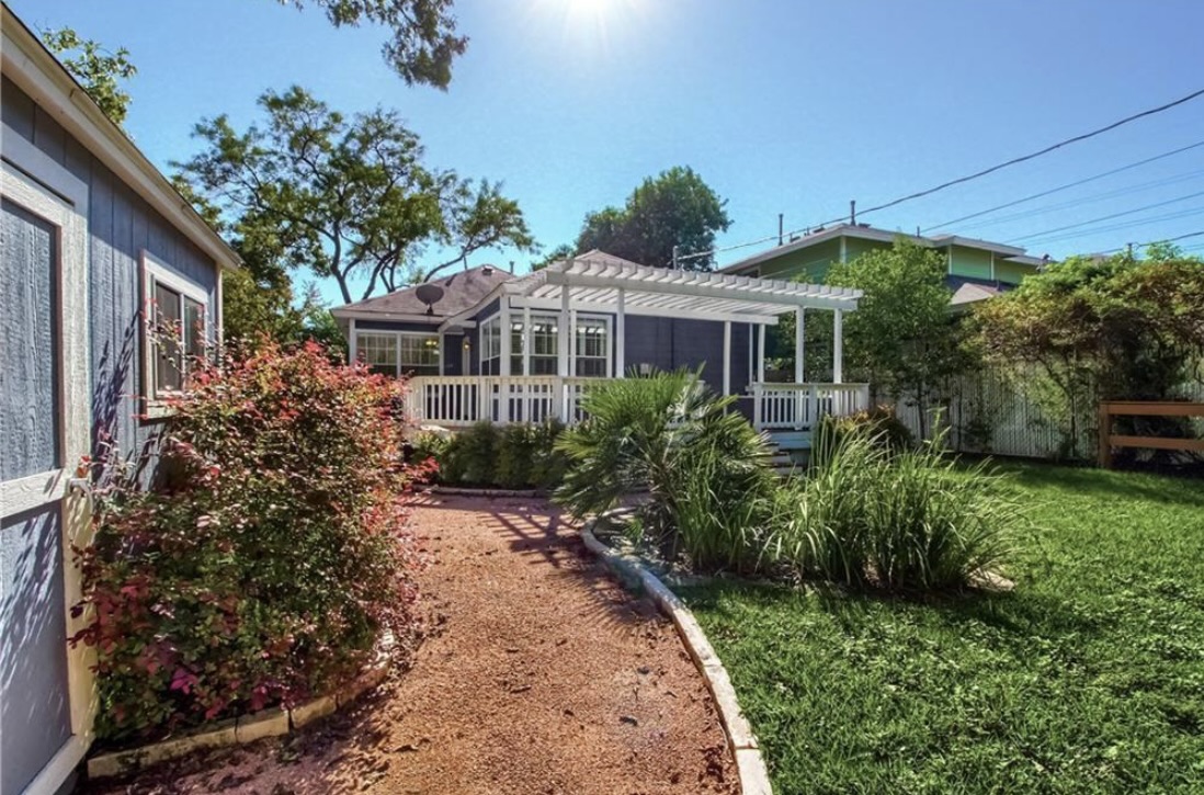 702 West N Loop Boulevard Austin, TX 78751 - Photo 18 of 23 A well-maintained yard and garden path lead to an inviting deck with a white pergola.