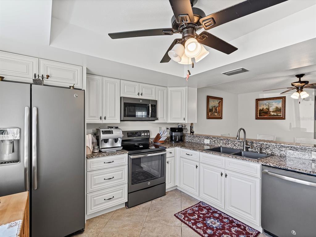 9615 Midiron Court, Unit 9615 New Port Richey, FL 34655 - Photo 13 of 36 a kitchen with stainless steel appliances a sink stove and refrigerator
