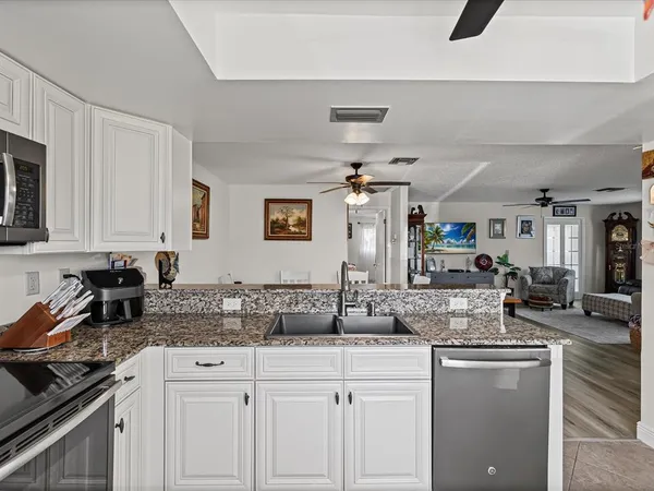 a kitchen with granite countertop a sink a stove cabinets and counter space