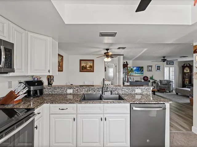a kitchen with granite countertop a sink a stove cabinets and counter space