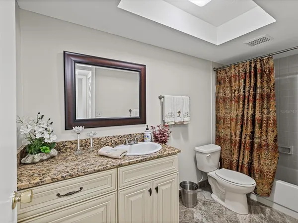 a bathroom with a granite countertop sink a toilet a mirror and shower curtain