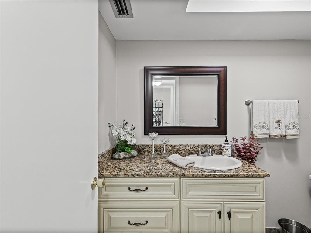 9615 Midiron Court, Unit 9615 New Port Richey, FL 34655 - Photo 24 of 36 a bathroom with a granite countertop sink and a mirror