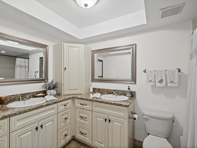 a bathroom with a granite countertop toilet sink and mirror