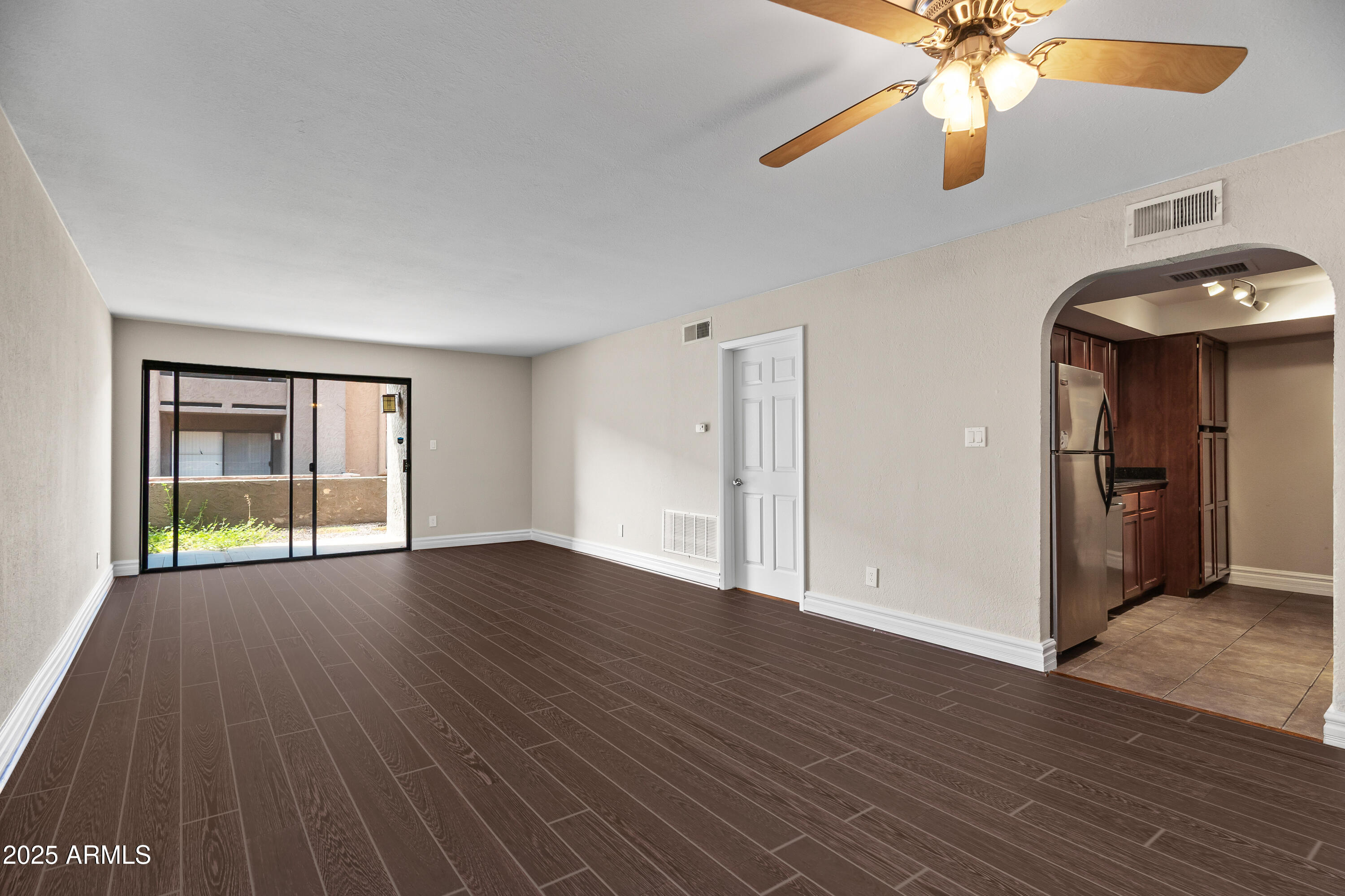 3825 East Camelback Road, Unit 114 Phoenix, AZ 85018 - Photo 20 of 21 an empty room with wooden floor fan and windows