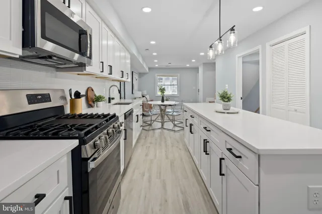 a large kitchen with stainless steel appliances granite countertop a lot of counter space a sink and dishwasher a stove top oven with wooden floor