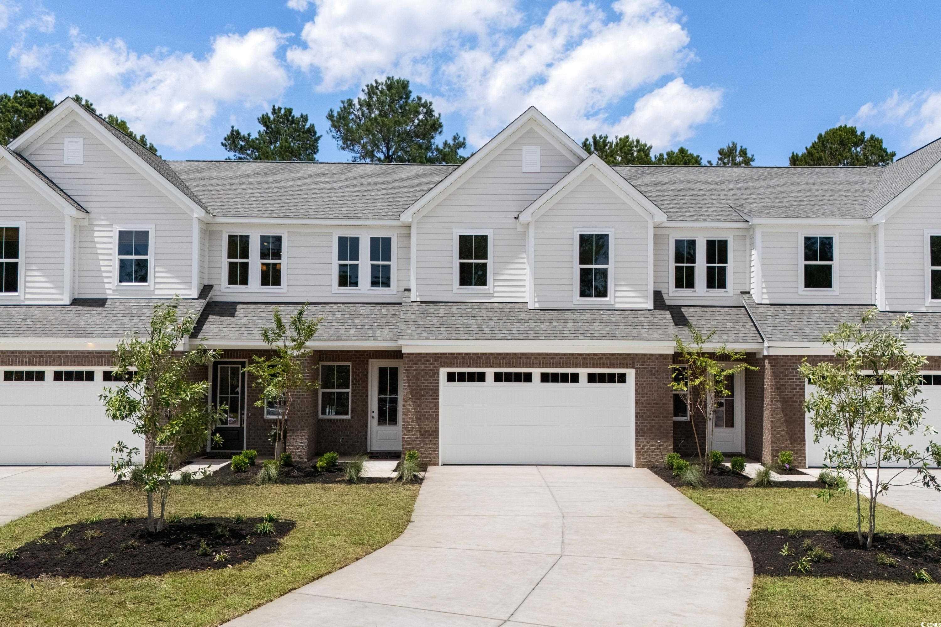 View of front of house with driveway, brick siding, roof with shingles, and a front yard