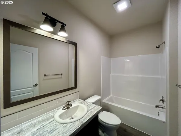 a bathroom with a granite countertop sink toilet a mirror and shower