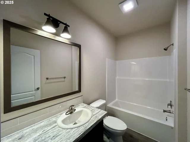 a bathroom with a granite countertop sink toilet a mirror and shower