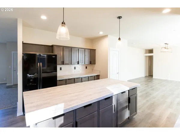 a kitchen with granite countertop a refrigerator a sink and wooden floor