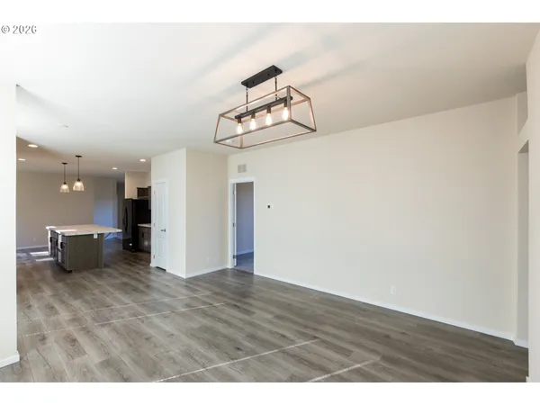 a view of an empty room with kitchen and chandelier